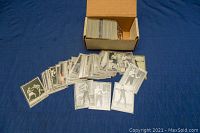 Boxing trading cards spread out in front of a box on blue surface. Cards are predominantly black and white and include images of historic fights and boxers.