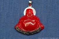 Front view of the red jade carved Buddha pendant showing the detailed carving and silver-tone metal bail and backing at the bottom.