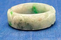 Front view of white and green jade carved bangle showing intricate detailing and green spots