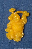 Front view of the yellow amber carved Buddha figurine showing detailed carving and glossy finish