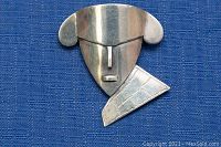 Front view of silver abstract face brooch on blue fabric, showing modernist design with geometric elements.