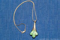 Full view of the necklace and pendant on blue textured fabric.