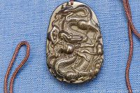 Close-up front view of brown quartz pendant with detailed dragon carving.