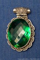 Front view of the 925 sterling silver pendant displaying the large green faceted stone and ornate silver border.