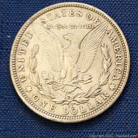 Reverse side of the 1884 Morgan silver dollar featuring the eagle with arrows and olive branch and denomination.