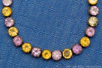 Close-up of bracelet showing round faceted stones in yellow, pink and green colors set in silver-tone bezels.