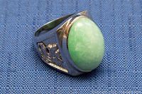 Front and slightly angled view of silver ring featuring large smooth oval green jade stone.