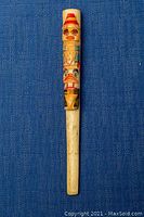 Full view of carved Native American Haida totem pole cigarette holder on blue background