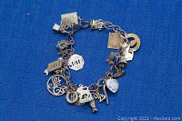Top view of the silver charm bracelet with visible charms such as a stop sign, heart, bell, and letters.