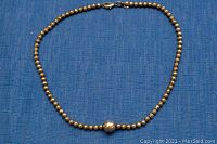 Full view of necklace laid flat on blue fabric