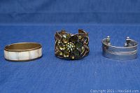 Three costume bangles arranged side by side on blue fabric background, showing the front views.