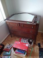 Front view of antique wooden dresser with detachable mirror placed on top.