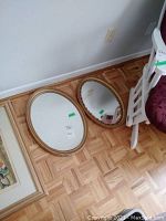 Photo of two oval mirrors placed on floor, showing overall size and wear on frames