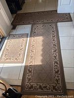 Photo of all three matching entrance mats arranged on floor showing size differences and decorative vine patterned border.