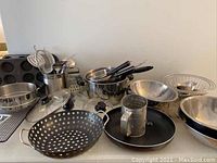 Wide view of all kitchen items arranged including pots, pans, bowls, and utensils.