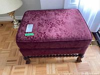 Front view of rectangular ottoman showing burgundy floral upholstery and wood legs