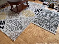 Large and small rugs placed together on hardwood floor showing patterns and condition.