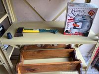 Yellow-handled axe with blue grip, Wonder Stitch compact sewing machine in box, and wooden wall shelf