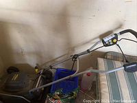 Photo showing the green electric Yardworks lawn mower with control handle and electric cord.