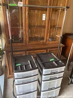 Full view showing metal coat rack with adjustable horizontal hanging bar and two black and transparent plastic storage units positioned below it.