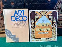 Two hardcover Art Deco design collector books side by side, showing front covers with titles and authors visible, placed in front of a decorative background.