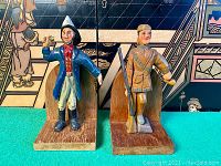 Front view of two hand-carved wooden folk art bookends with painted figures and brass lip bases.