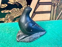 Three photos showing different angles of the vintage carved soapstone bird figurine, highlighting the carved feather details, bird posture, and textured base.