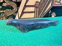 Side profile of the soapstone seal figurine showing the smooth polished body and etching details on face and flippers.