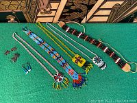 Photo of five Native American style beadwork necklaces and chokers arranged on green cloth, showing a variety of colors and patterns including a thunderbird and geometric designs.