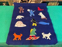 Full view of dark blue fabric wall hanging with multiple colorful appliqué pieces representing Inuit culture.