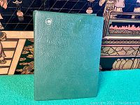 Closed green hardcover stockbook showing textured vinyl cover and embossed logo
