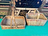 Two old woven baskets side by side, showing their size and color differences.