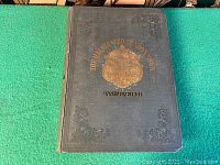 Front cover showing dark cloth binding with gold embossed title and crest