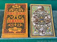 Front covers of 1870 and 1875 Public Ledger Almanacs side by side on a green surface.