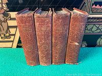 Front side photo showing four antique volumes of The Cornhill Magazine in red embossed cloth covers.