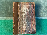 Front cover of the book showing the half leather binding and marbled paper boards with visible wear and scuffs.