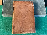Top cover of the 1846 leather bound book showing wear and stains on brown leather surface.
