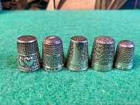 Front view of five sterling silver thimbles arranged side by side