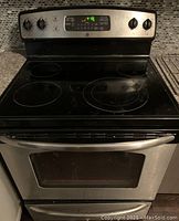 Front view of GE stainless steel electric range with smooth black ceramic glass cooktop and digital control panel