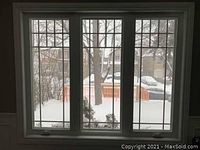 Interior view of white vinyl casement window showing three sashes with grid pattern and snowy exterior backdrop