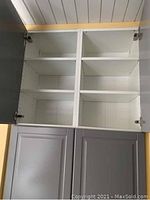 Interior view of upper cabinet with doors open showing adjustable white shelving.