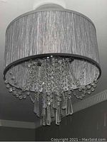 Photo of ceiling light fixture showing gray fabric drum shade and hanging glass crystal drops