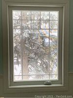 Front view of white vinyl casement window with grid design showing crank handle and trim.