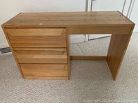 Solid wooden desk with three drawers on left side, natural wood finish, some surface wear visible