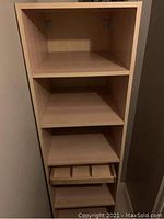 Tall wooden cabinet with multiple shelves and a drawer containing three dividers.