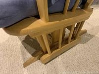 Close-up of the wooden base showing scratches and the glider mechanism.