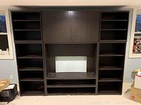 Front view of the large dark brown IKEA TV cabinet with multiple open shelves, large storage doors above the TV space, and drawers below. Shows overall size and structure.