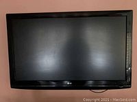 LG 52-inch flatscreen TV mounted on wall with black frame and screen showing reflections and scratches.