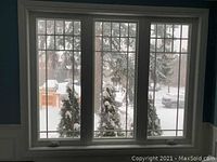 Triple-panel white vinyl casement window installed in wall with decorative grid and crank handle visible