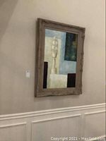 Side angle view of the framed blue, beige, and brown abstract canvas art hung on wall.